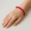 Pulsera roja de jade natural hecha a mano sobre fondo neutro, ideal para protección energética y chakra raíz
