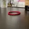 Pulsera roja de jade natural hecha a mano sobre fondo neutro, ideal para protección energética y chakra raíz