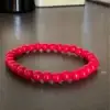 Pulsera roja de jade natural hecha a mano sobre fondo neutro, ideal para protección energética y chakra raíz Paz Gabriel